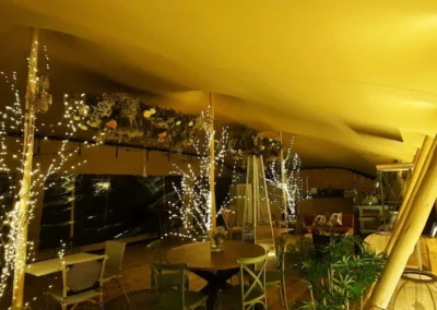 interior de espacio bajo cubierta de carpa beduina iluminado con postes de madera